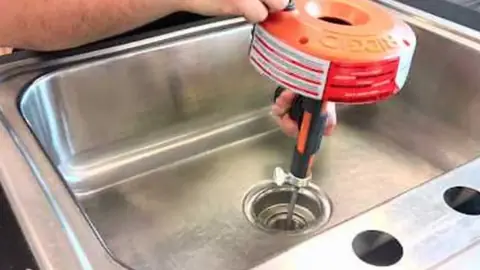Hand-cranked drain auger in a kitchen sink drain